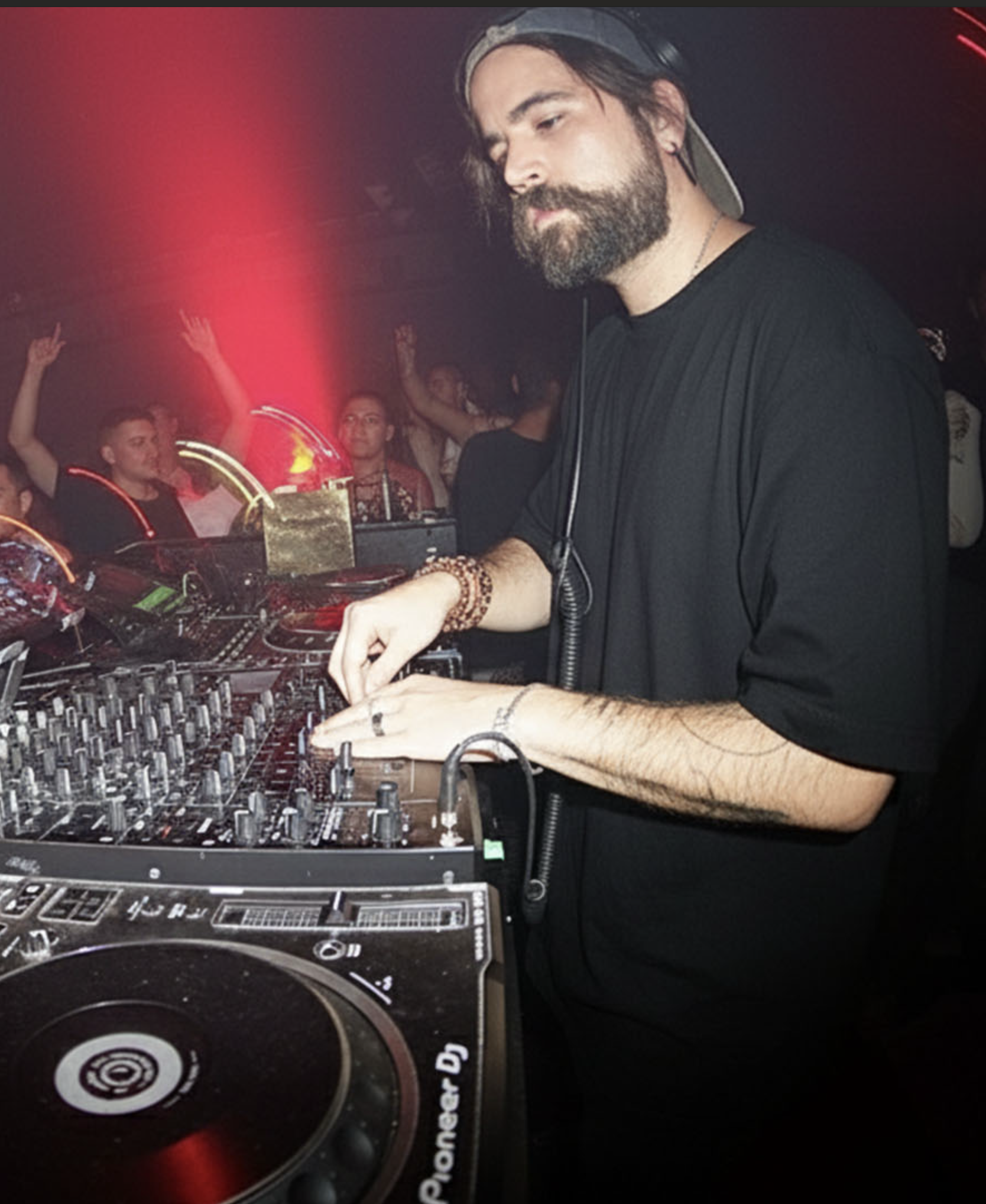DJ mezclando música en un ambiente oscuro con plantas
